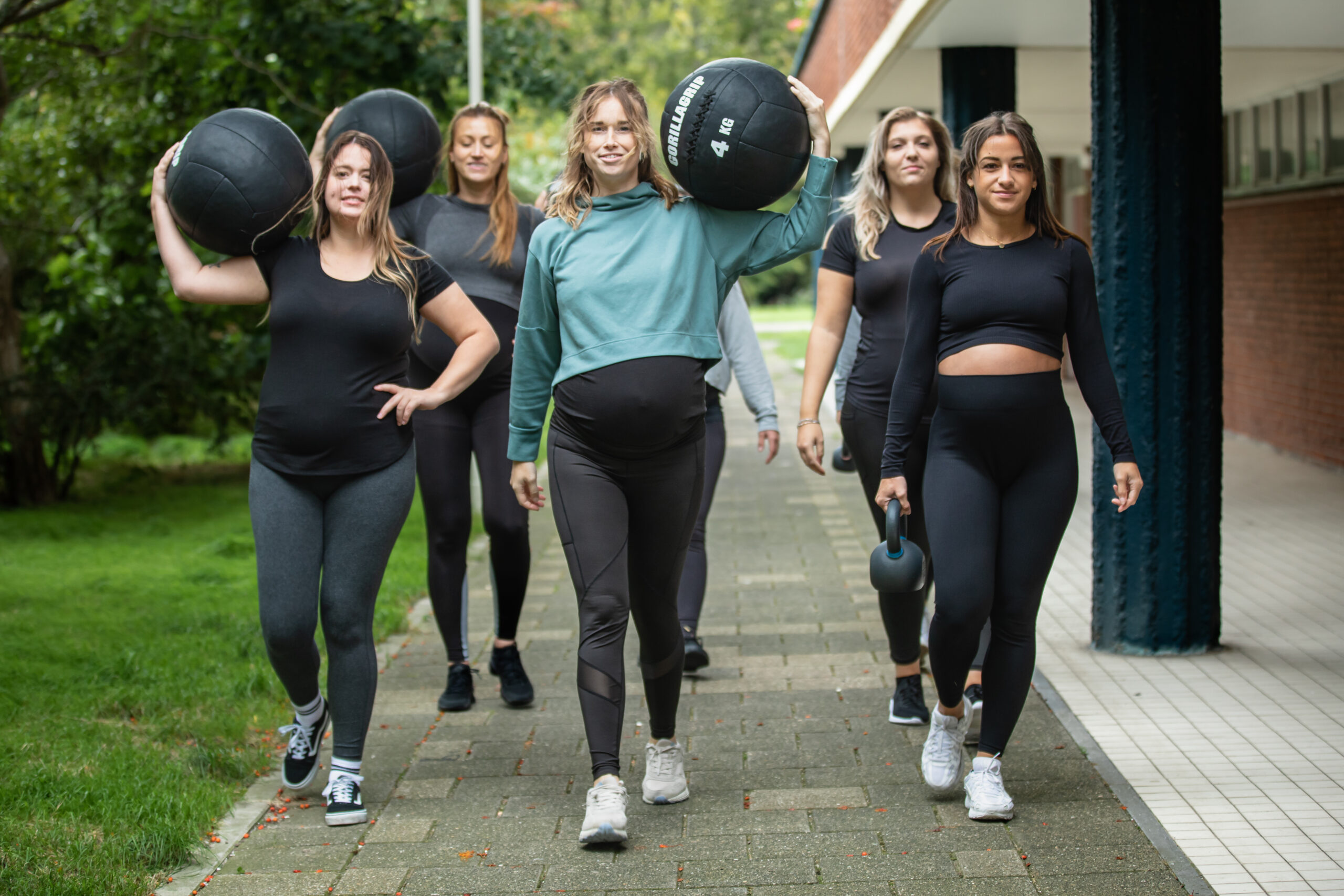 Zwangere vrouw traint met een stang tijdens de Powermama Cursus